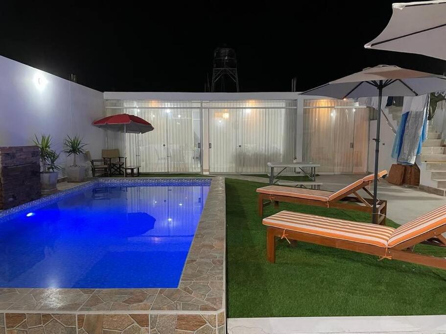 La PuntaDepartamento de playa con piscina en estreno的一个带长凳和遮阳伞的游泳池