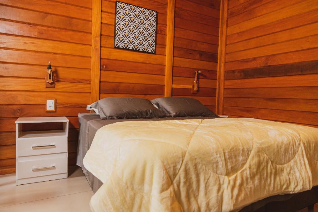 多明戈斯马丁斯Pousada Gagno的木质墙壁和木地板客房的一张床位