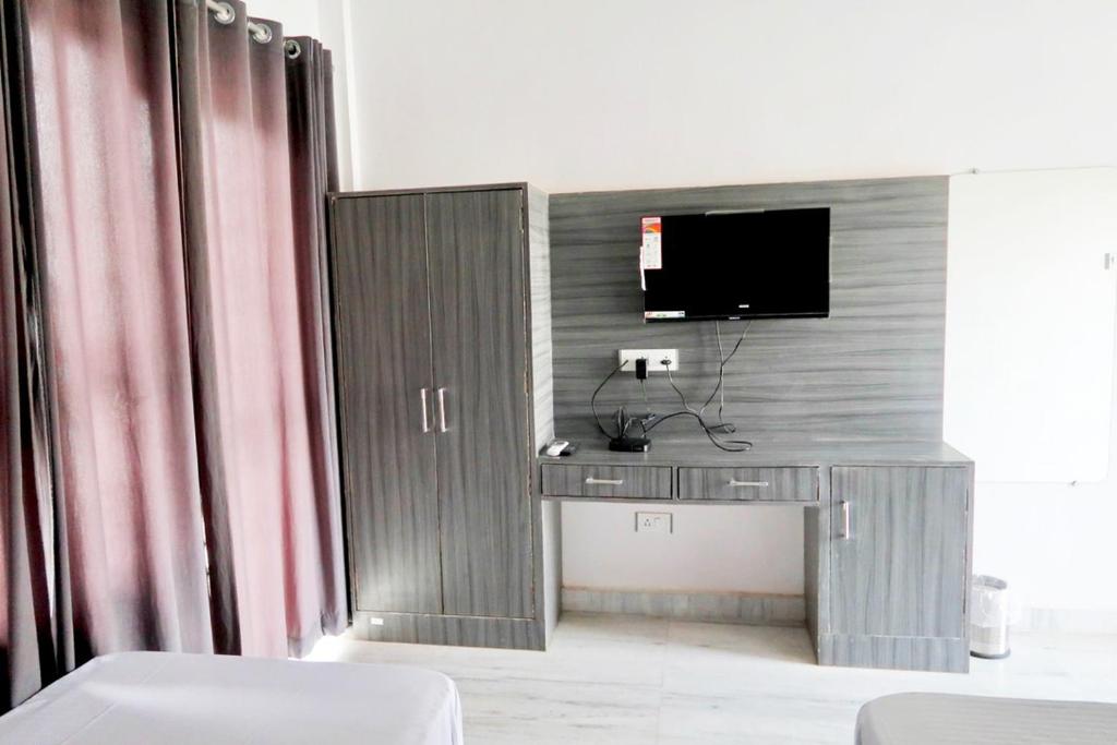 克久拉霍Aarambh Residency的一间设有一张桌子的房间,墙上有一台电视机