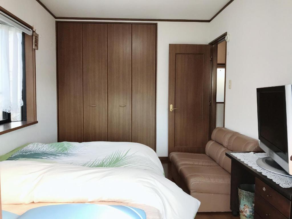 相模原市friendly 民宿的一间卧室配有一张床、一张沙发和一台平面电视。
