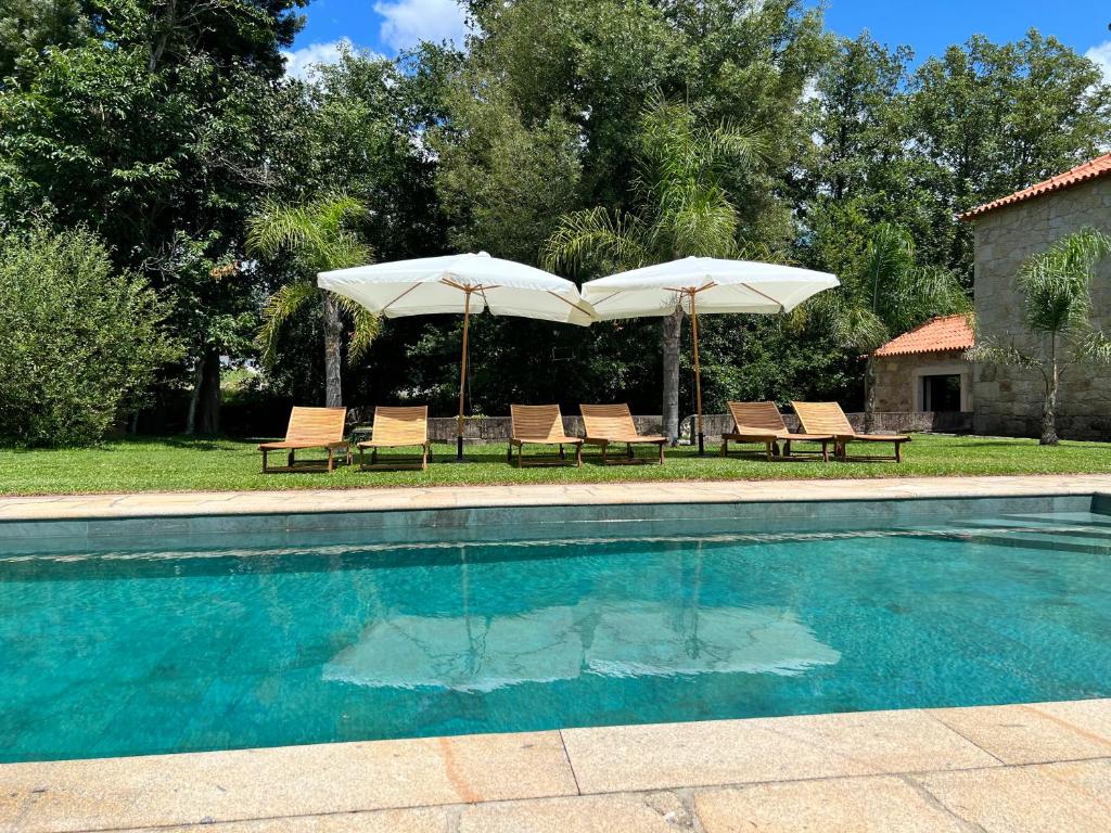 蓬德利马Quinta do Moinho da Ínsua的一个带两把遮阳伞和两把椅子的游泳池
