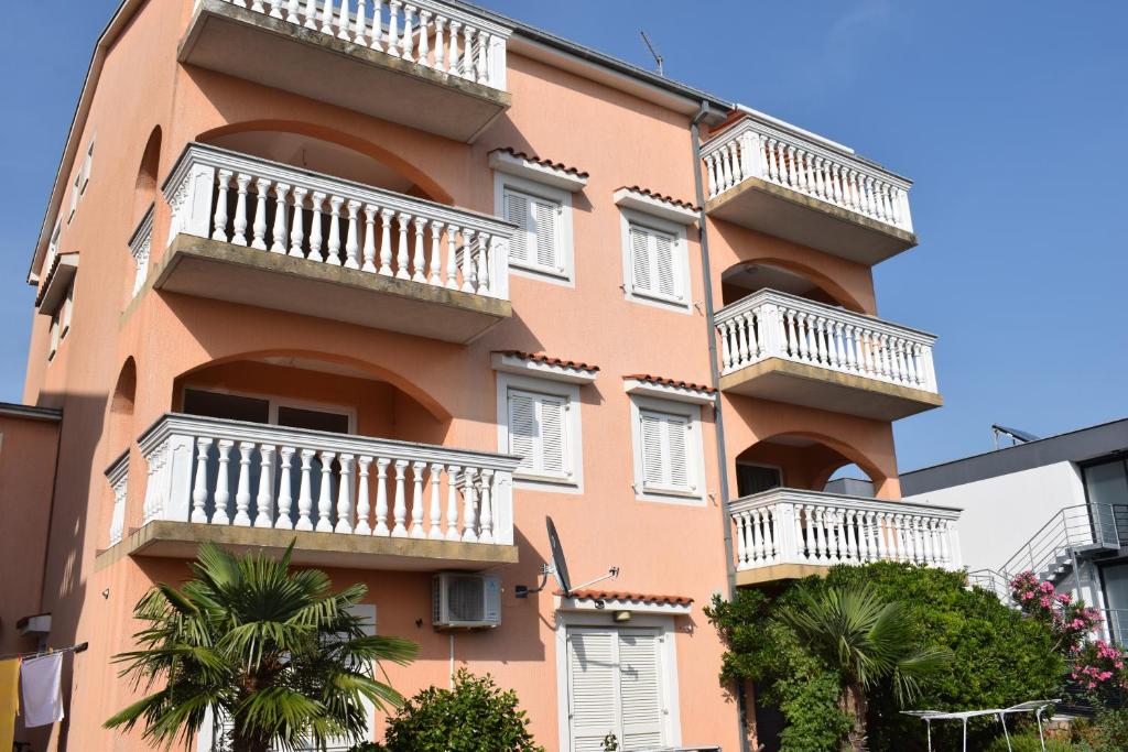 茨里克韦尼察拉万达公寓的一座橙色的建筑,设有白色的阳台,并种植了棕榈树