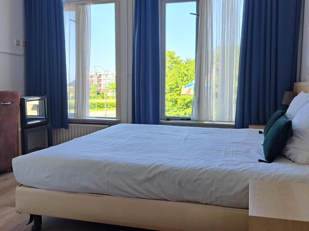 代尔夫宰尔博文格罗宁根餐厅酒店的一间卧室配有一张大床,配有蓝色窗帘和窗户。