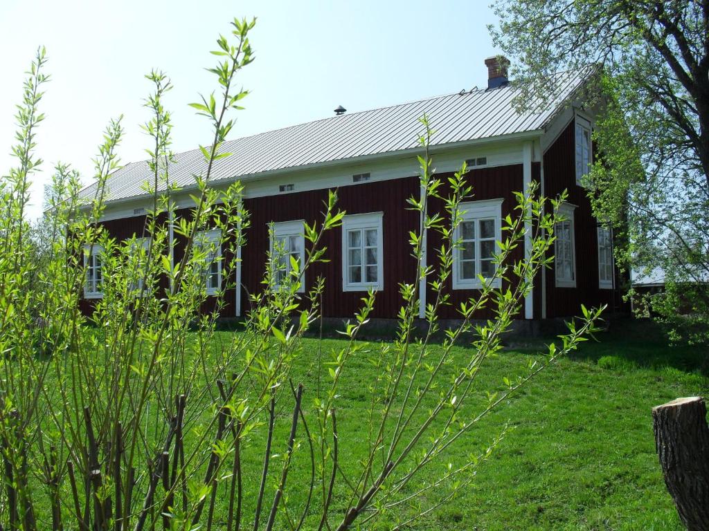 克里斯蒂娜城Old Farmhouse Wanha Tupa的红色的房子,有白色的窗户和绿色的草地