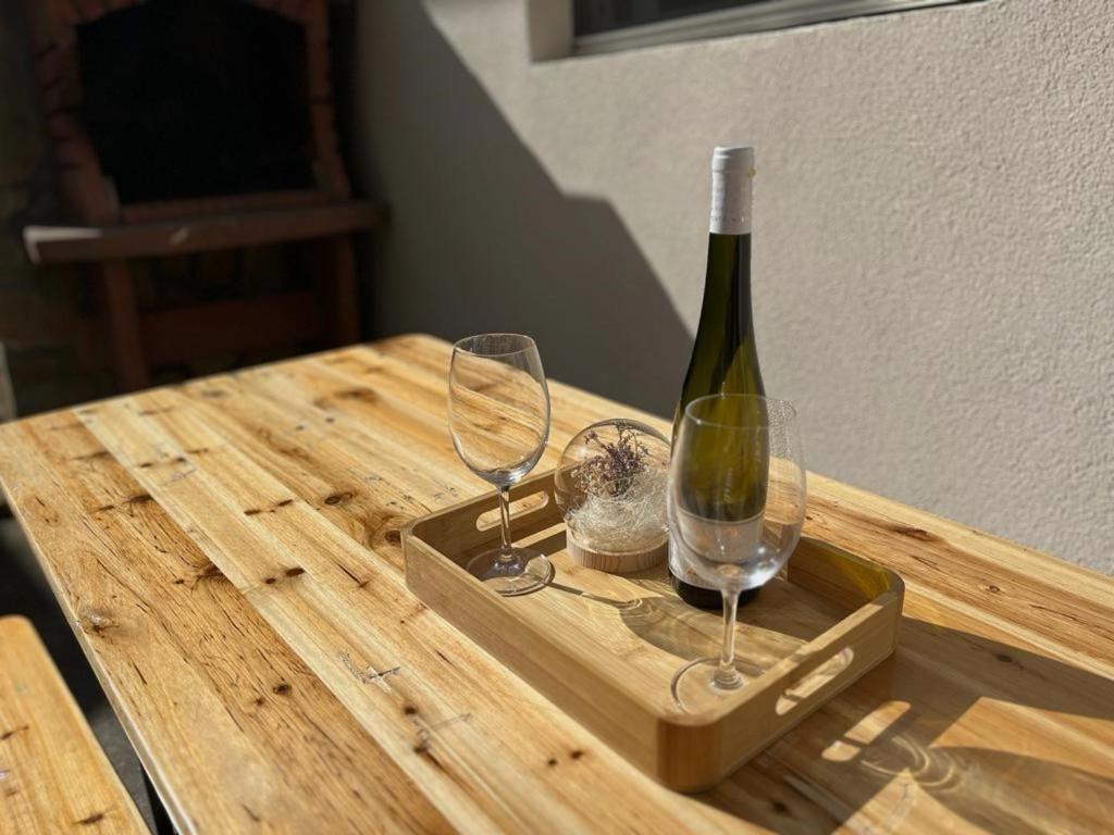 斯塔里格勒Secret Place Apartment的木桌旁的一瓶葡萄酒和两杯酒