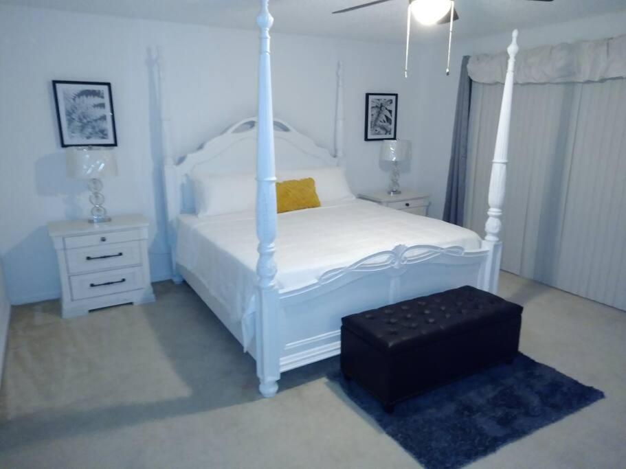 基西米Amore's luxurious 4 bedroom home.的白色卧室设有天蓬床和凳子
