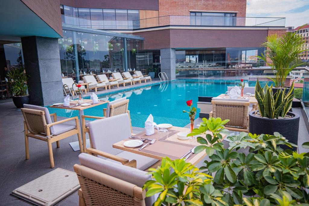 加德满都Hotel Barahi Kathmandu的酒店庭院设有游泳池和桌椅