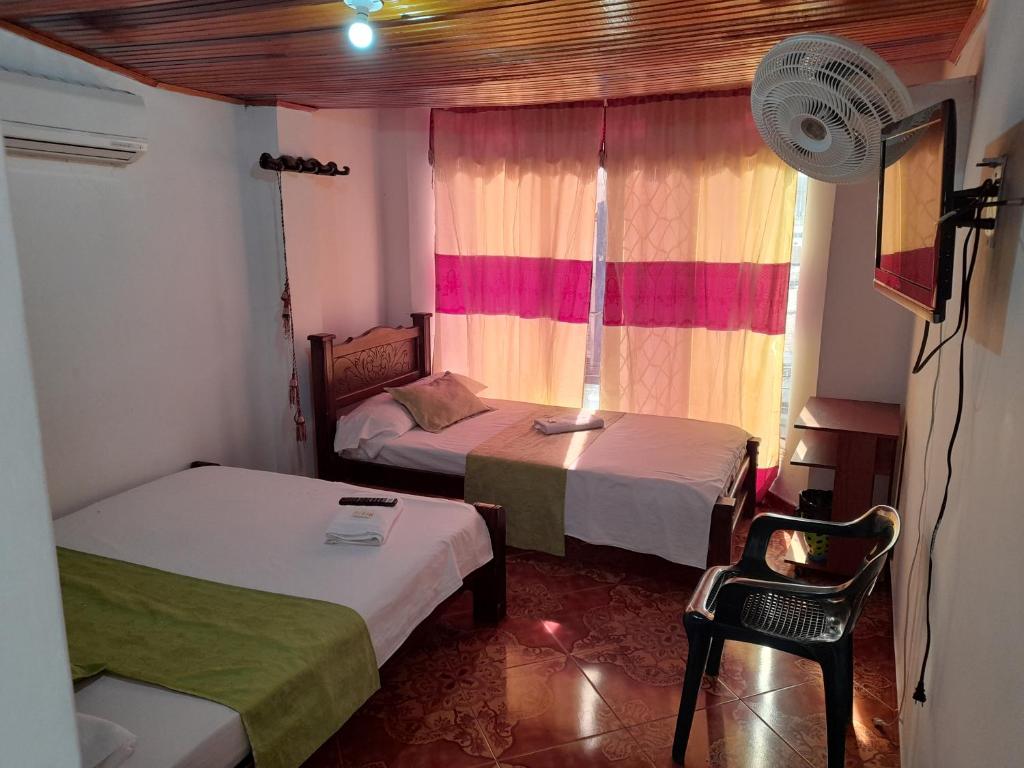 弗洛伦西亚HOTEL NUEVO SOL的一间卧室设有两张床和一个带风扇的窗户。