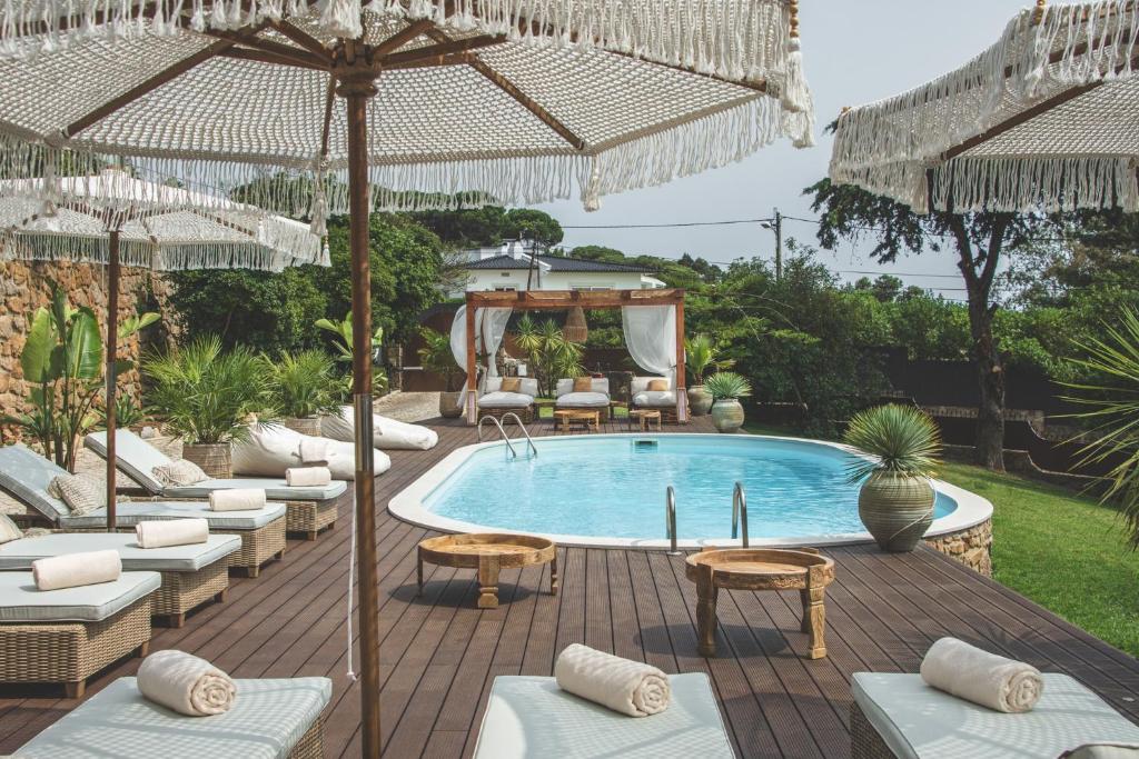 埃斯托利尔Villa Pietra Estoril Eco Guesthouse的一个带椅子和遮阳伞的游泳池