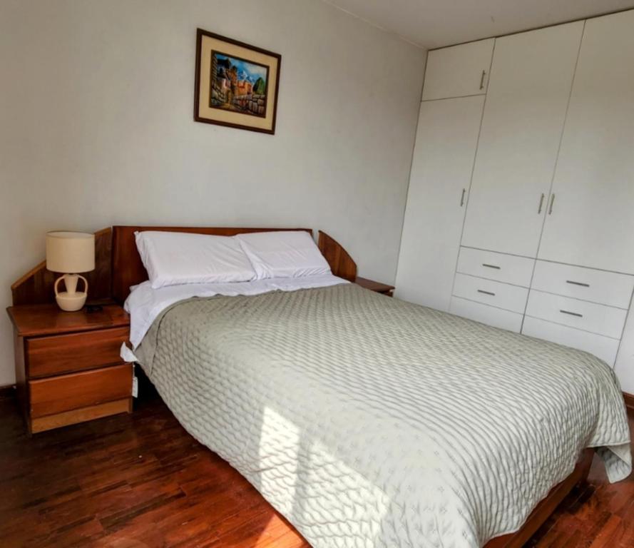 利马Casa Cultura II的一间卧室配有一张床和一个带灯的床头柜