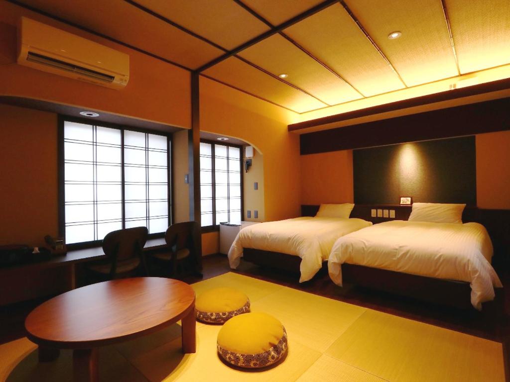 KihokuchoKii no Matsushima的酒店客房设有两张床、一张桌子和一张桌子。