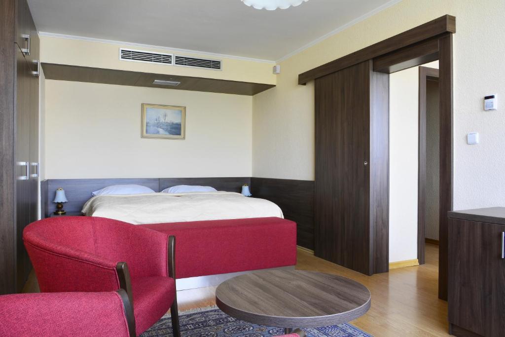 布拉格奥林匹克酒店的一间卧室配有一张床和一张红色椅子