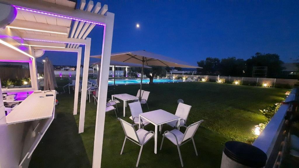 佩斯卡拉Luxury Pool Suites - Città Bianca的一个带桌椅的庭院和一个夜间游泳池