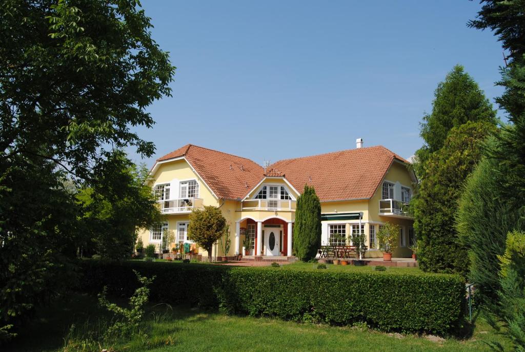 杜瑙基利蒂Villa Hedi Panzió的红色屋顶的大型黄色房屋