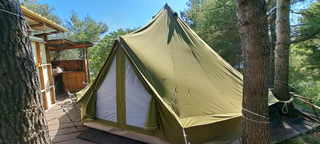 柳巴茨LJUBAC GLAMPING BELL TENT Robinson的树旁甲板上的黄色帐篷