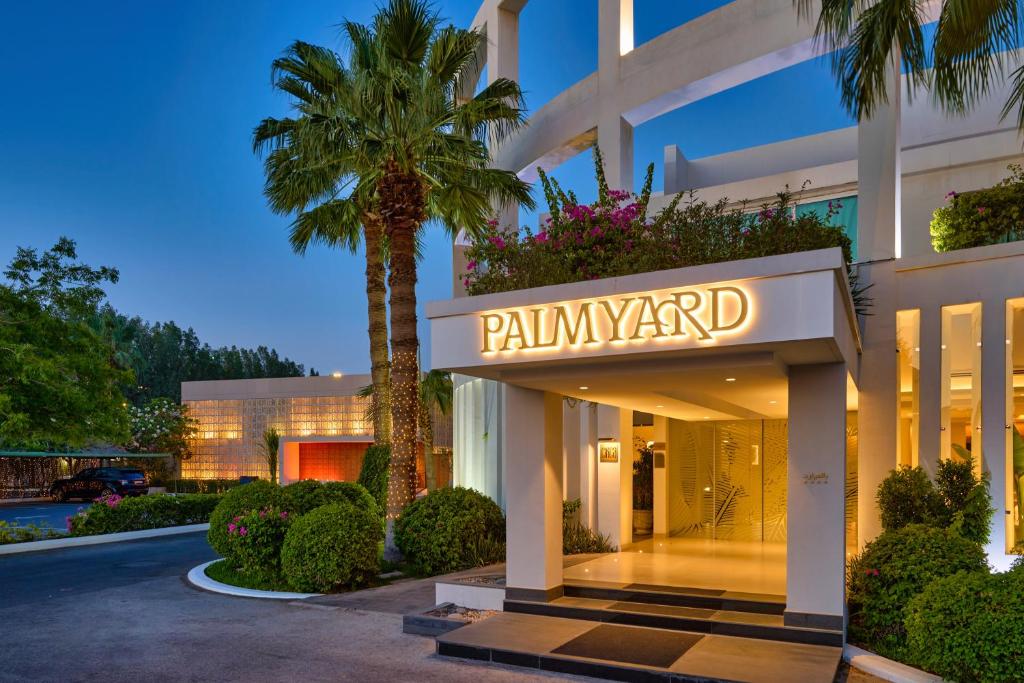 麦纳麦Palmyard Hotel的一座建筑前有棕榈树的酒店