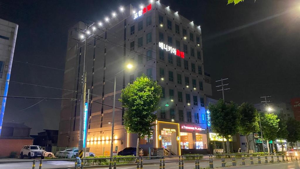 浦项浦项高丽良宵酒店的一座高大的建筑,晚上在建筑的一侧有标志