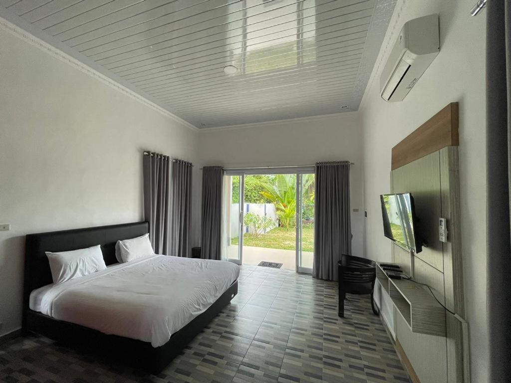 MuntokPondok Sahang Cottages的一间卧室配有一张床和一台平面电视