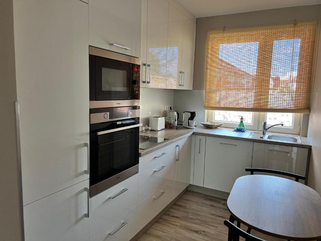 斯维诺乌伊希切Apartament BARI的厨房配有白色橱柜和黑烤箱。