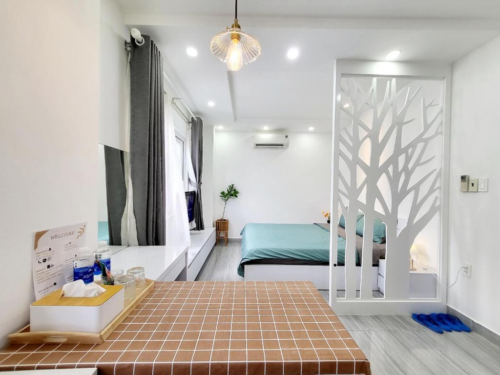 胡志明市MơMơ Residence的一间卧室配有一张床,另一间卧室墙上有一棵树。