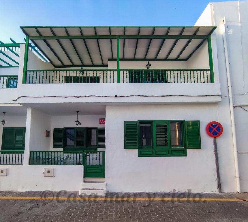 普拉亚布兰卡Casa mar y cielo的白色的建筑,设有绿色的窗户和阳台