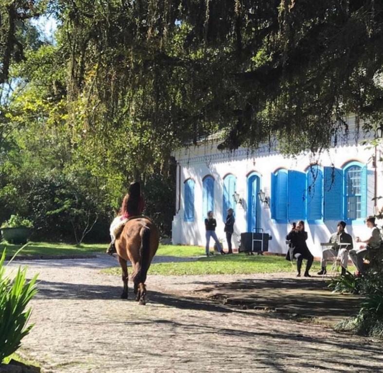 佩洛塔斯Charqueada Santa Rita Pousada de Charme的一名在建筑物前骑马的女人