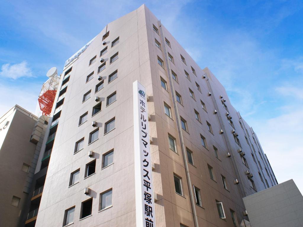 平冢市HOTEL LiVEMAX BUDGET Hiratsuka Ekimae的建筑的侧面有标志