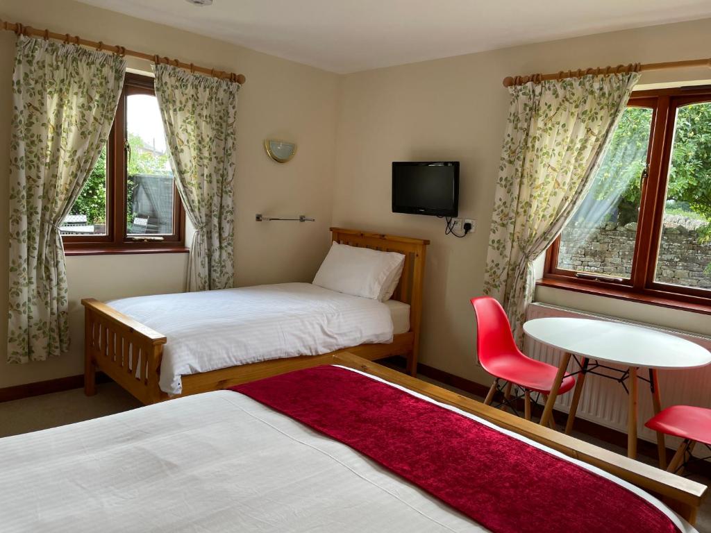 彭里斯Sunset House B&B的酒店客房带两张床和一张桌子以及椅子。