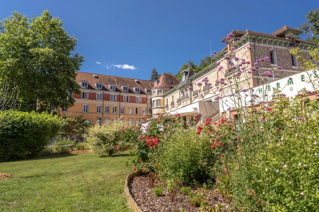 Évaux-les-BainsLe Grand Hôtel, The Originals Relais的一座花园,在一座建筑前种有鲜花
