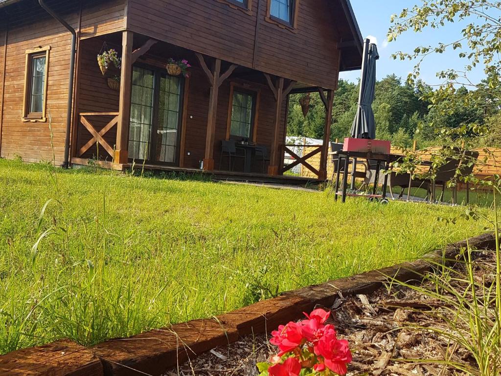 OsiekWooden Holiday Home in Skrzynia with Terrace的院子里的小木屋,带花