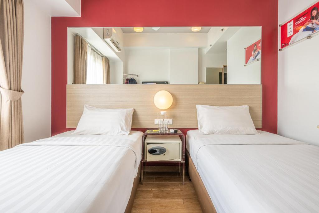巨港Monoloog Hotel Palembang的红色墙壁客房的两张床