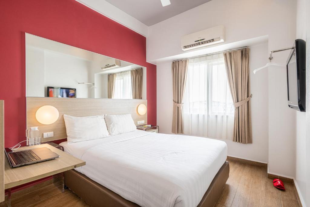 马卡萨Monoloog Hotel Makassar的酒店客房配有一张床、一张书桌和一台笔记本电脑