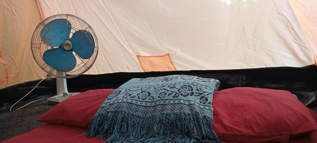 Sam Chukสามชุกบ้านสวน的一张带枕头的床和帐篷旁边的风扇