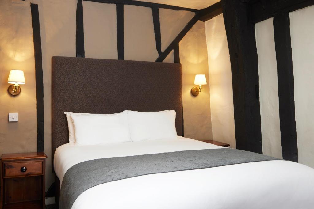 霍尔斯特德Bull Hotel by Greene King Inns的一间卧室配有一张带白色床单的大床