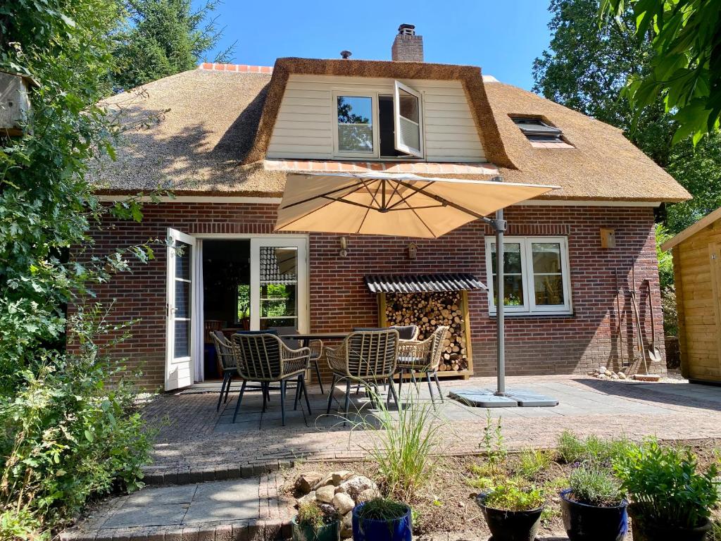 伊皮Huisje aan de Bosrand - Veluwe的庭院配有桌椅和遮阳伞。