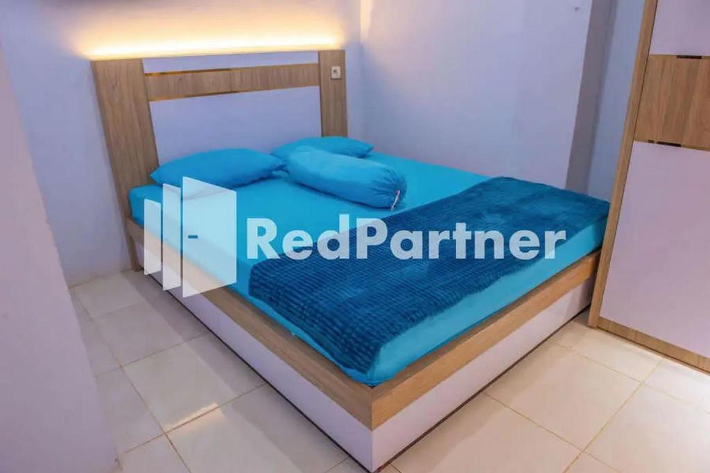PalopoHotel Rai's Palopo Exclusive Mitra RedDoorz的一张床上的房间,上面有红色的伙伴标志