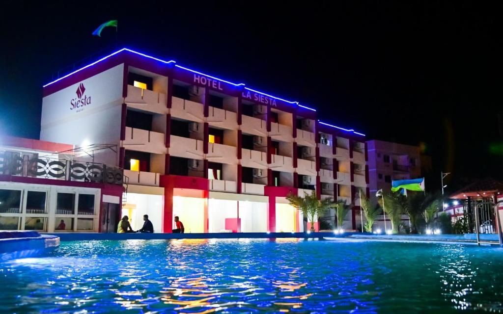 吉布提SIESTA HOTEL的一家晚上在游泳池前的酒店
