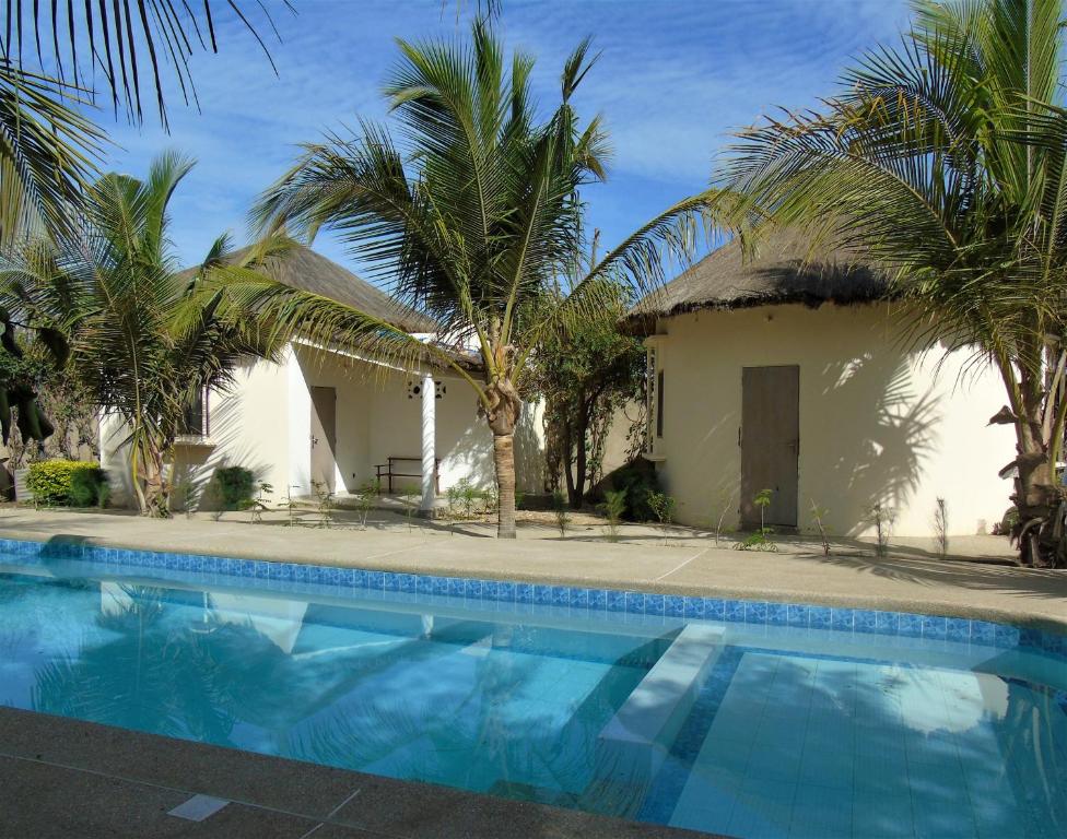 MbodièneWouroBa的一座带游泳池和棕榈树的房子