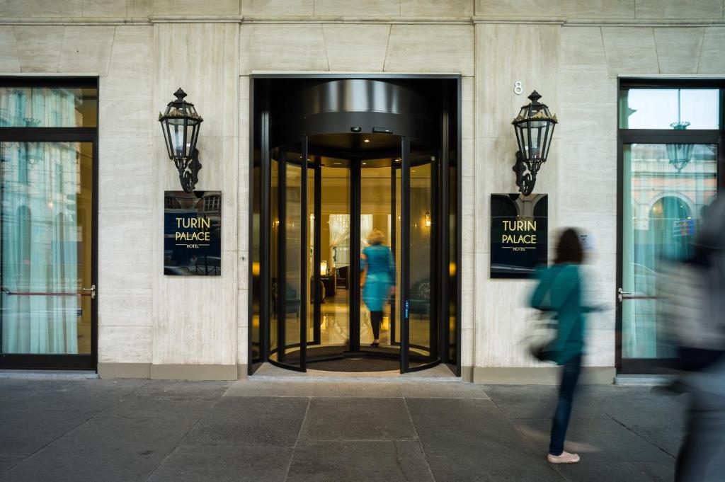 都灵都灵宫殿酒店的走在有旋转门的建筑物中的女人