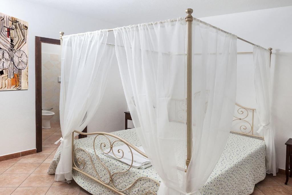 奥列纳Managheri Wine Bar的卧室配有带白色窗帘的天蓬床