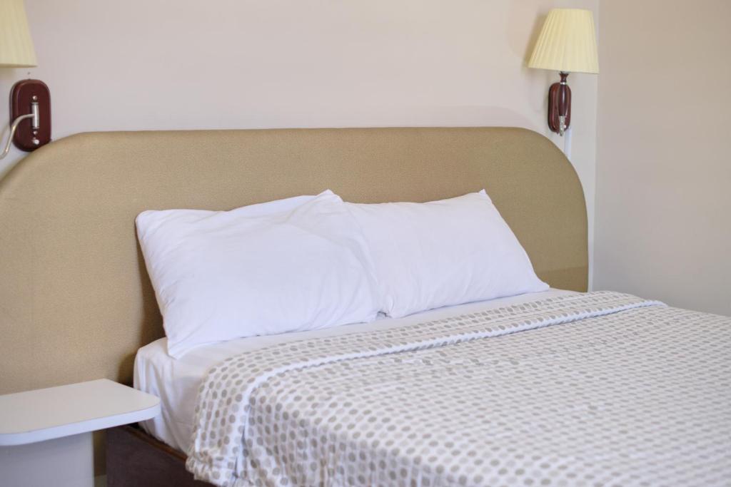 帕拉马里博Gess Hotel的床上铺有白色枕头的床