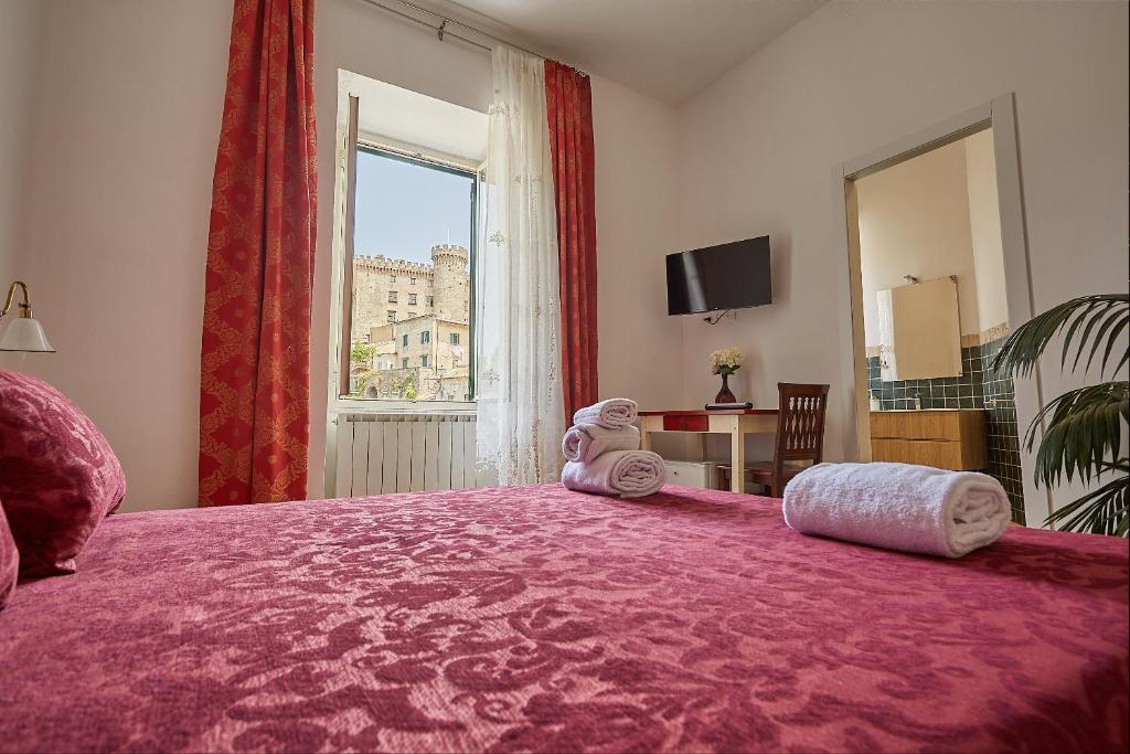 布拉恰诺LE CAMERE di VITTORIA的卧室设有一张大粉色床和大窗户