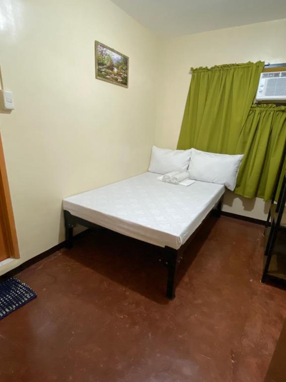 宿务ACHIEVERS DORMITORY的一张位于带绿色窗户的房间内的床铺