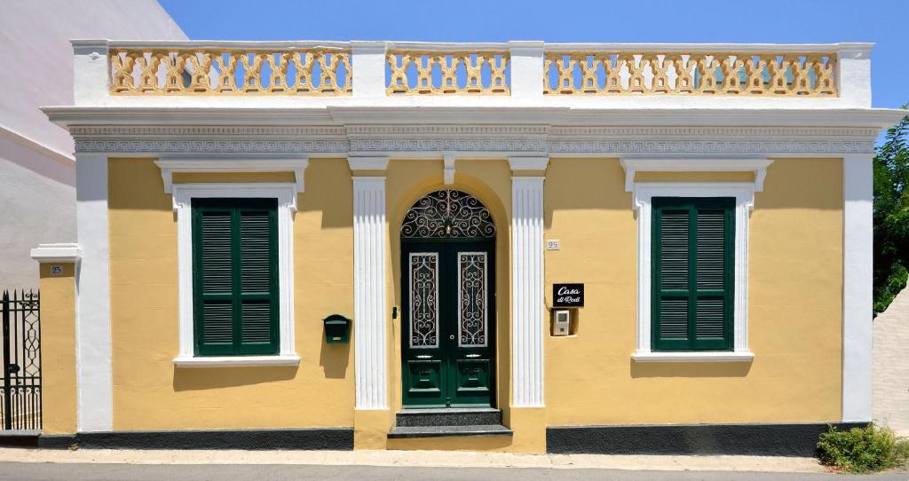 罗德镇Casa Di Rodi的黄色的房屋设有绿门和阳台