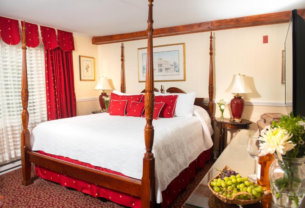 纽波特纽波特美洲帆船旅馆的一间卧室配有一张带红色枕头的四柱床