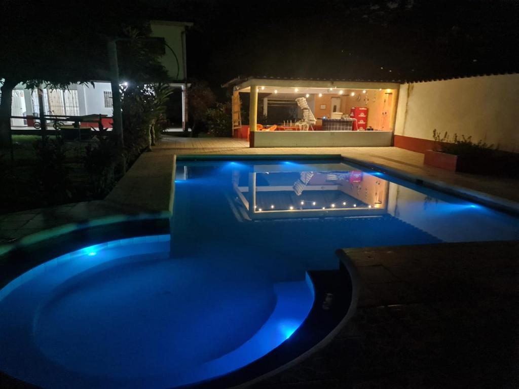 EscuintlaChalet El Paraiso的夜晚的游泳池里点着蓝色的灯光