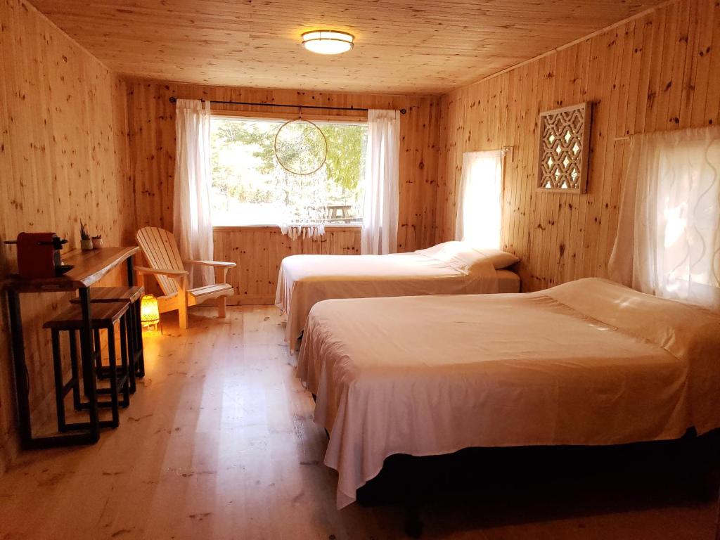 托伯莫里New Buddha Bing Unique Experience Cottage and Cabins的一间卧室设有两张床、一张桌子和一个窗口。