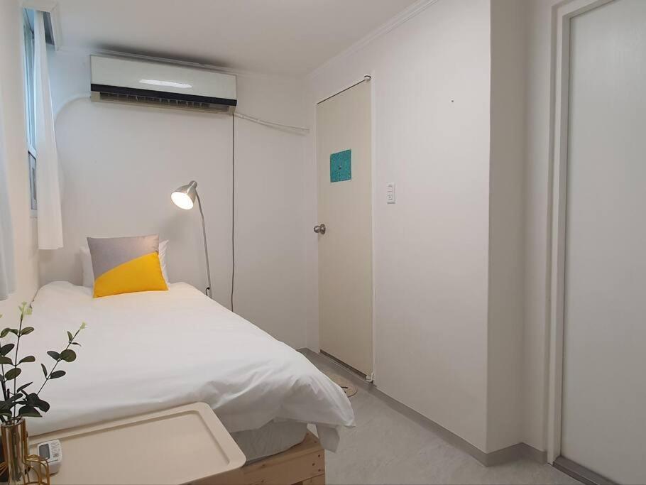 首尔Coco Stay的白色卧室配有一张带黄色枕头的床