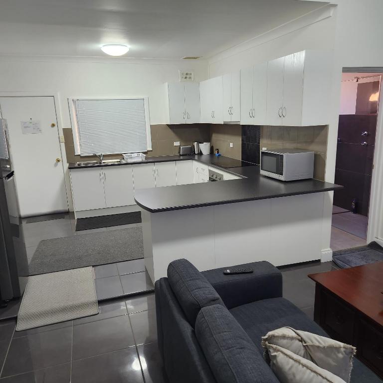 布罗肯希尔City Villa 39 Blende st Broken Hill NSW 2880的一间厨房,内设白色橱柜和沙发