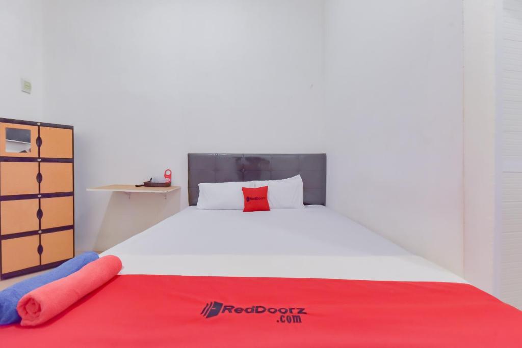 打拉根Reddoorz near Juwata Airport Tarakan的卧室配有一张大白色床和红色毯子